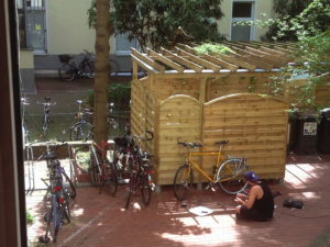 Mann sitzt im Berliner Hinterhof vor Fahrrad